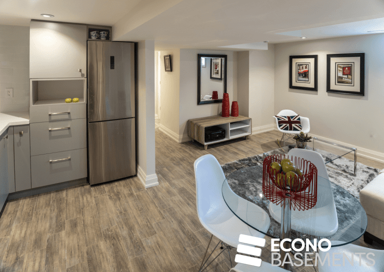 A basement development in Calgary completed by Econo Basement Builders. It shows a living space, small dining space with a table and 3 chairs, and a small kitchen on the side